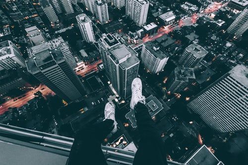 Aerial photography of man sitting on top of building with high rise buildings view at daytime building photography building aesthetic high rise building