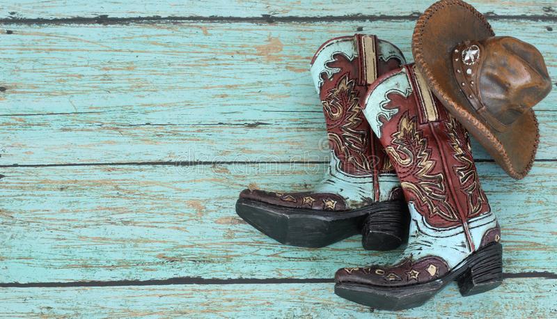 Cowboy boots and hat on a teal background stock photo