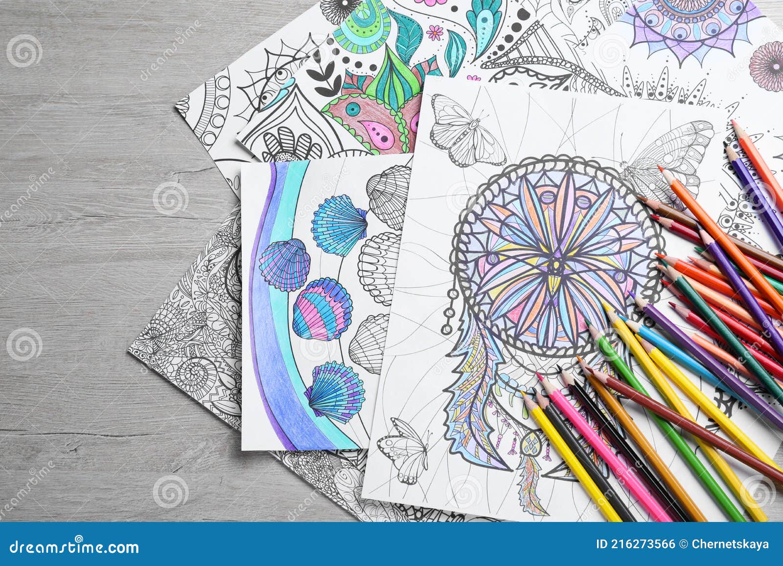 Antistress coloring pages and pencils on light wooden table flat lay stock photo