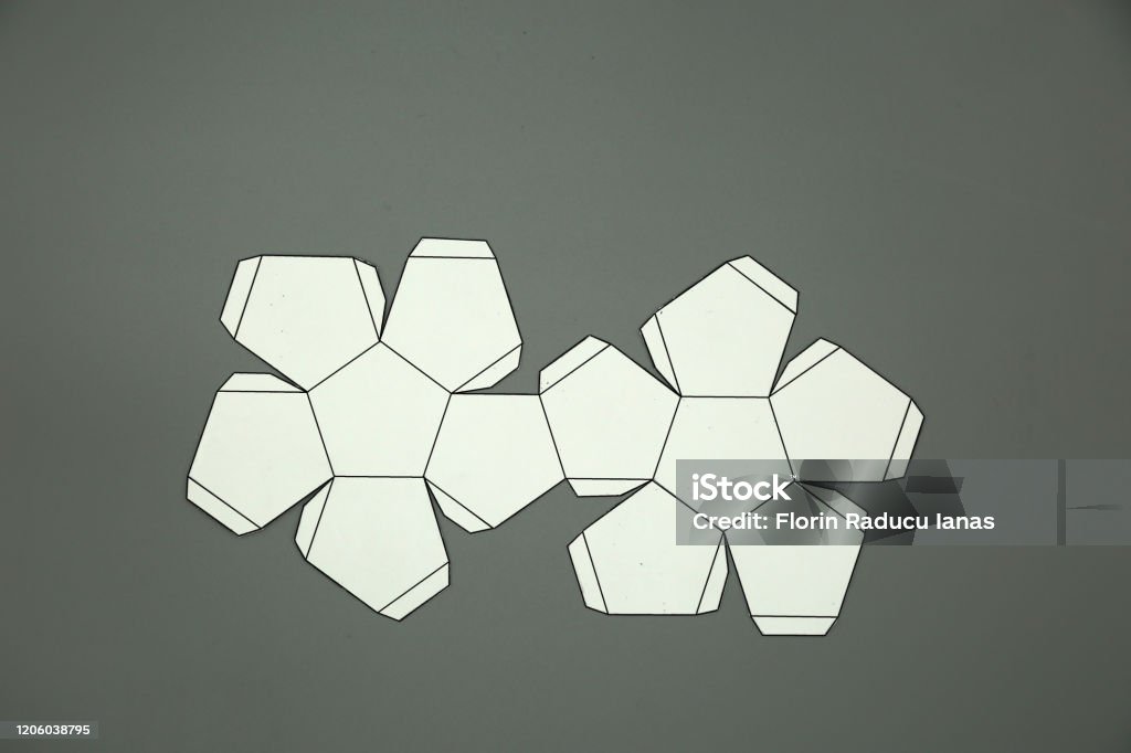 Geometric shape cut out of paper and photographed on grey backgrounddodecahedron d shape foldable to form a d shape or a solid stock photo