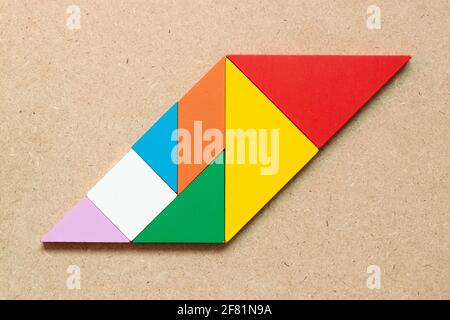 Color tangram puzzle in parallelogram shape on wood background stock photo