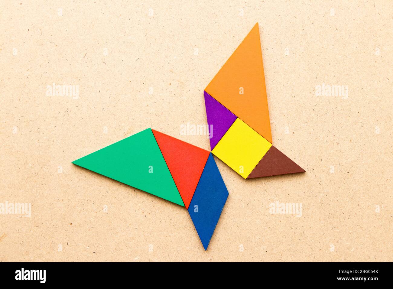 Color tangram in butterfly shape on wood background stock photo