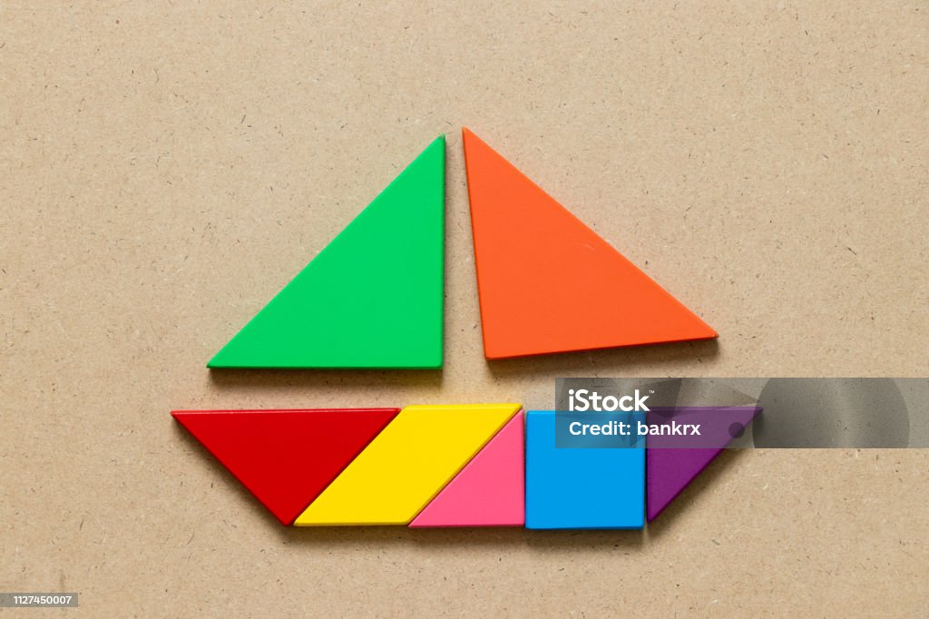 Color tangram puzzle in sail boat shape on wood background stock photo