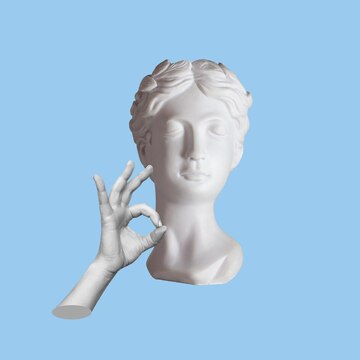 Premium photo antique female statues head shows the ok gesture with hand isolated on a blue color background