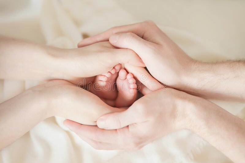 Parents hands hold in their hands the legs of their child on a white background parental love and tenderness stock photo