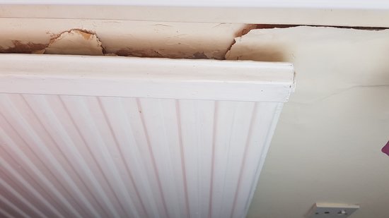 Peeling wallpaper above and behind the radiator