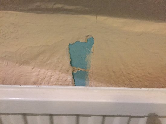 Wallpaper peeling on bathroom wall behind radiator