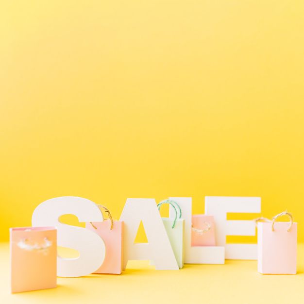 Free photo small pink shopping bag in front of letter sale on yellow background yellow background sale poster logo online shop